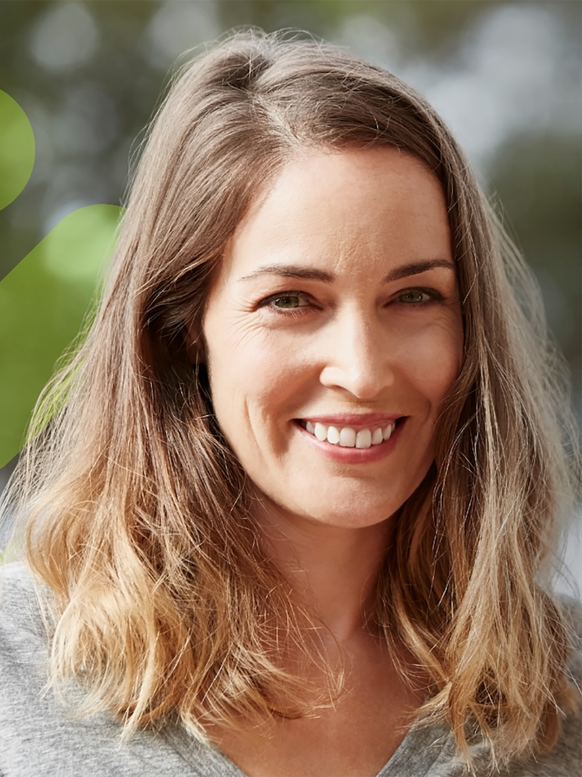 A healthy-looking adult smiling warmly in a natural outdoor setting